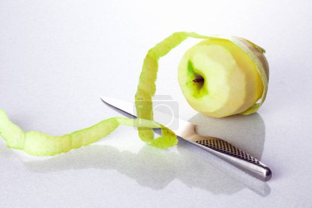 Photo for Peeled fresh green apple and knife on a white background - Royalty Free Image