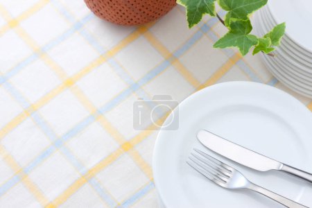 Photo for Fork and knife on white plate. Ivy plant on the table - Royalty Free Image