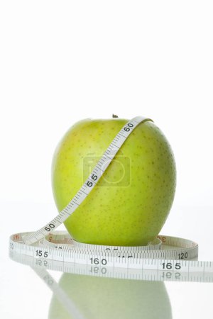 Téléchargez les photos : Pomme et ruban à mesurer sur fond blanc. Concept de régime - en image libre de droit