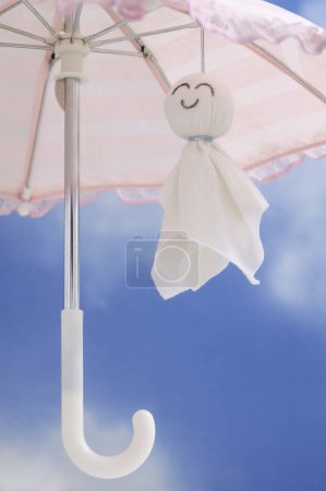 Photo for Umbrella and cotton handmade doll on a blue sky background, romantic toy made of white textile - Royalty Free Image