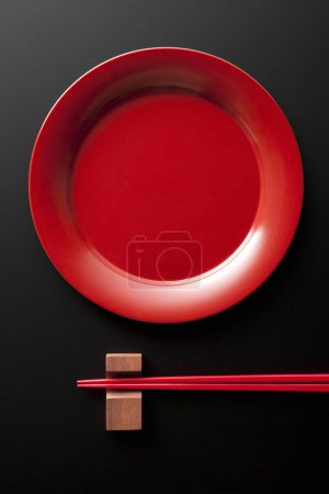 Photo for Top view of red plate and chopsticks on black background - Royalty Free Image