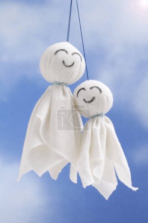 Téléchargez les photos : Deux poupées en coton faites à la main sur un fond bleu ciel, jouets romantiques en textile blanc - en image libre de droit