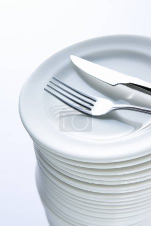 Photo for Fork and knife on stack of white plates - Royalty Free Image