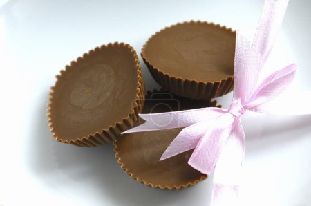 Foto de Caramelos de chocolate con lazo rosa en el fondo, de cerca - Imagen libre de derechos