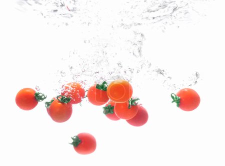 Téléchargez les photos : Tomates rouges dans l'eau sur fond blanc - en image libre de droit