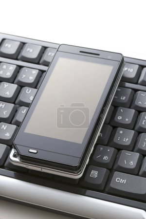 Photo for Close-up view of modern mobile phone on the computer keyboard - Royalty Free Image