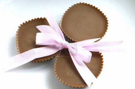 Photo for Chocolate candies with pink bow on background, close up - Royalty Free Image