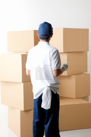 Photo for Young man in white uniform with cardboard boxes on warehouse - Royalty Free Image