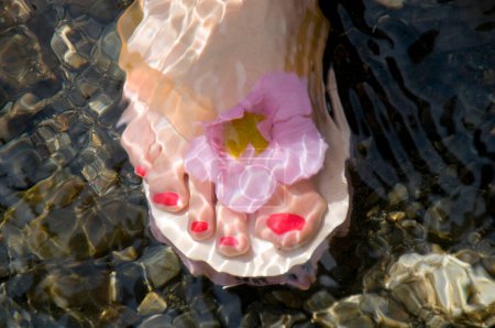 Téléchargez les photos : Vêtements de pieds féminins Tongs dans l'eau - en image libre de droit