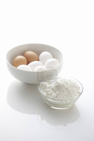 Téléchargez les photos : Oeufs blancs avec farine dans un bol et n fond blanc - en image libre de droit