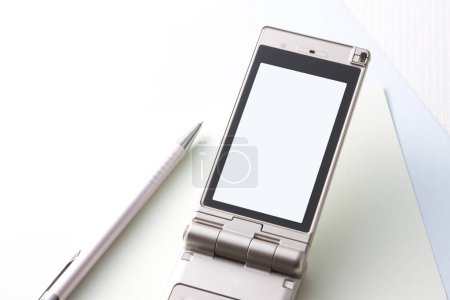 Téléchargez les photos : Vue rapprochée de l'appareil téléphonique moderne isolé sur fond de table blanche - en image libre de droit