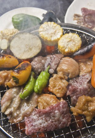 Téléchargez les photos : Vue rapprochée de la personne cuisinant de la viande et des légumes sur le gril dans un restaurant japonais - en image libre de droit