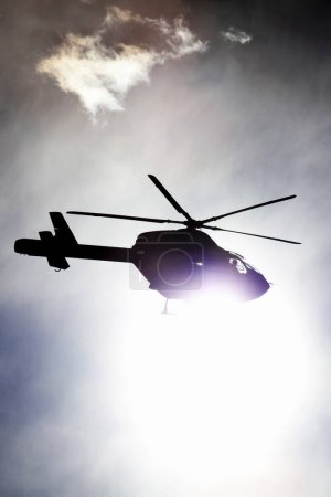 Foto de Silueta de un helicóptero en el cielo sobre fondo natural - Imagen libre de derechos
