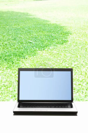 Téléchargez les photos : Ordinateur portable à écran blanc sur herbe verte avec espace de copie pour votre texte. - en image libre de droit