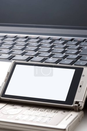 Téléchargez les photos : Téléphone portable moderne placé soigneusement sur un clavier d'ordinateur. - en image libre de droit