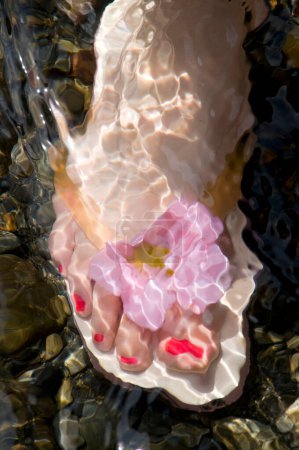 Foto de Pies femeninos con chanclas en el agua - Imagen libre de derechos