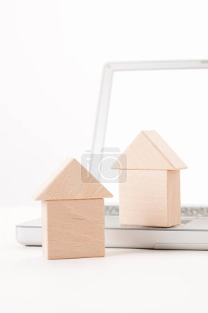 Téléchargez les photos : Ordinateur portable avec modèles de maison sur table blanche - en image libre de droit