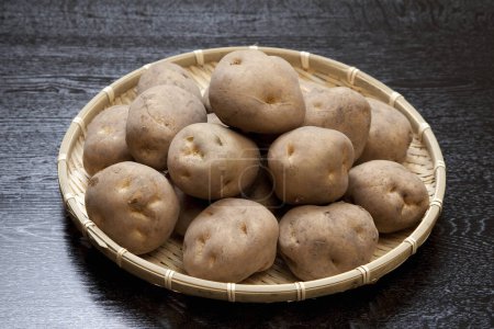 Téléchargez les photos : Vue rapprochée des pommes de terre crues mûres dans un panier en osier sur une table en bois - en image libre de droit