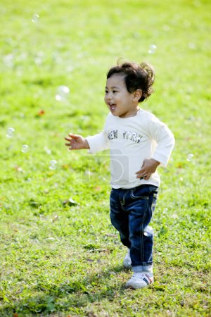 Téléchargez les photos : Mignon asiatique garçon jouer sur l 'herbe dans l' parc - en image libre de droit