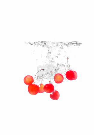 Foto de Bayas de cereza en un chorrito de jugo sobre un fondo blanco - Imagen libre de derechos