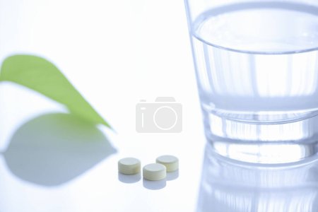 Téléchargez les photos : Verre d'eau et des pilules sur fond de lumière - en image libre de droit
