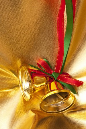 Foto de Campanas de navidad doradas con lazo sobre fondo de tela - Imagen libre de derechos