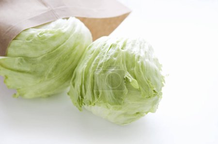 Foto de Coles verdes frescas en bolsa de papel sobre mesa blanca - Imagen libre de derechos