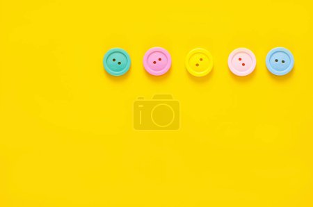 Téléchargez les photos : Vue de dessus des boutons colorés sur fond jaune - en image libre de droit