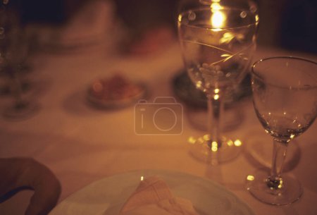Photo for Tableware with empty wineglasses reflecting candle light - Royalty Free Image