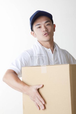 Photo for Tired delivery man with  cardboard box in warehouse - Royalty Free Image