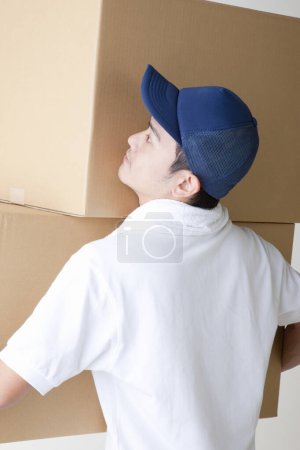 Téléchargez les photos : Livreur avec boîtes en carton dans l'entrepôt - en image libre de droit