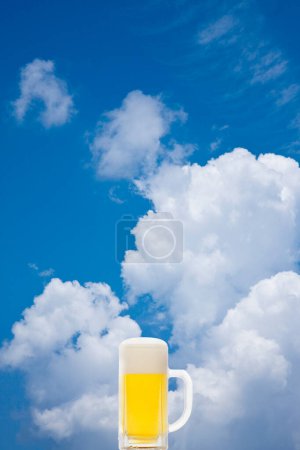 Téléchargez les photos : Verre de bière froide avec mousse sur fond bleu ciel - en image libre de droit
