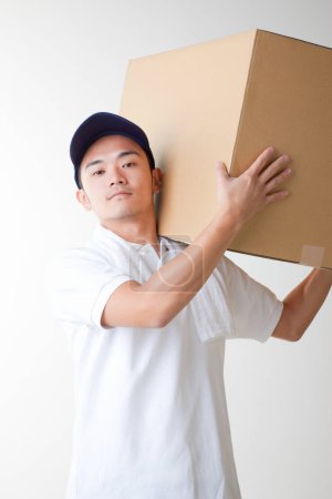 Téléchargez les photos : Livreur avec boîte en carton dans l'entrepôt - en image libre de droit