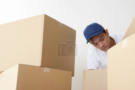 Téléchargez les photos : Asiatique homme emballage boîtes pour la livraison, isolé sur fond blanc - en image libre de droit