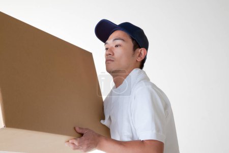Téléchargez les photos : Livreur fatigué avec boîte en carton dans l'entrepôt - en image libre de droit