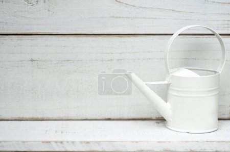 Photo for Empty vintage watering can on white wooden background. - Royalty Free Image