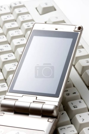 Téléchargez les photos : Smartphone placé sur un clavier d'ordinateur, prêt à l'emploi. - en image libre de droit