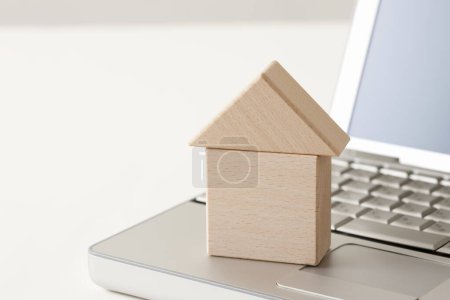 Photo for Laptop with house model on white table - Royalty Free Image