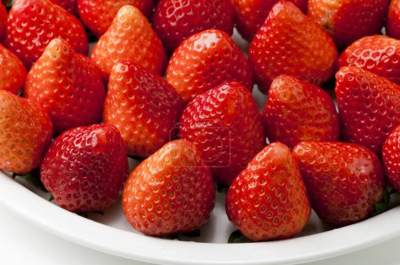 Photo for Close-up view of ripe red strawberries on white plate - Royalty Free Image