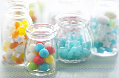Foto de Frascos de vidrio con caramelos de colores en la mesa - Imagen libre de derechos