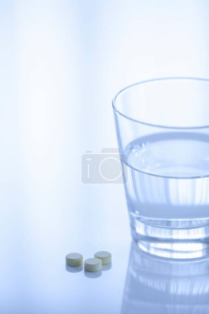 Téléchargez les photos : Verre d'eau et des pilules sur fond de lumière - en image libre de droit
