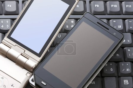 Téléchargez les photos : Vue rapprochée du téléphone portable moderne sur le clavier de l'ordinateur - en image libre de droit