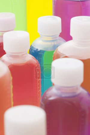 Téléchargez les photos : Vue rapprochée de bouteilles en plastique colorées de liquide sur fond clair - en image libre de droit