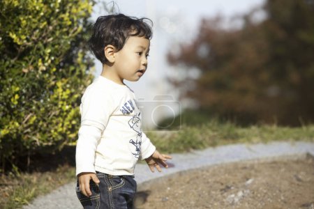 Photo for Cute asian boy playing on the grass in park - Royalty Free Image