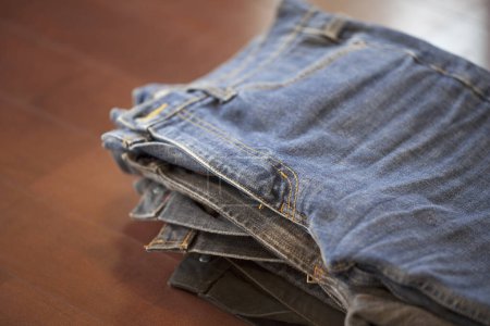 Photo for Stack of jeans on a wooden table background, close up - Royalty Free Image