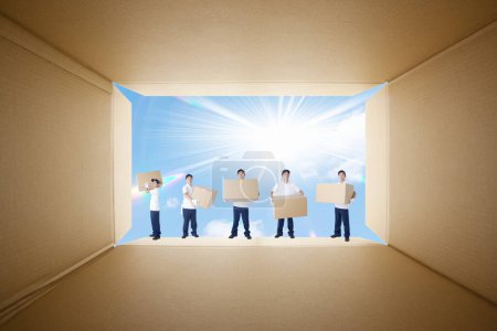 Photo for Delivery men  standing in a row in cardboard box against sky - Royalty Free Image