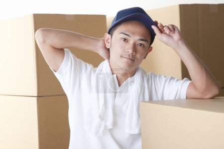 Téléchargez les photos : Jeune homme asiatique avec des boîtes en carton sur fond - en image libre de droit