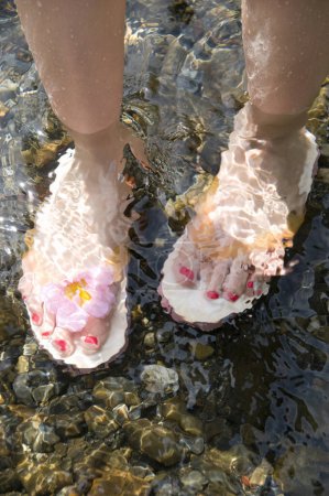 Téléchargez les photos : Vêtements de pieds féminins Tongs dans l'eau - en image libre de droit