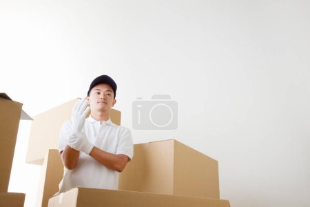 Téléchargez les photos : Livreur avec boîtes en carton dans l'entrepôt - en image libre de droit