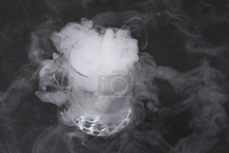 Weißer Rauch im Glas mit der Wirkung von Trockeneis auf dunklem Hintergrund